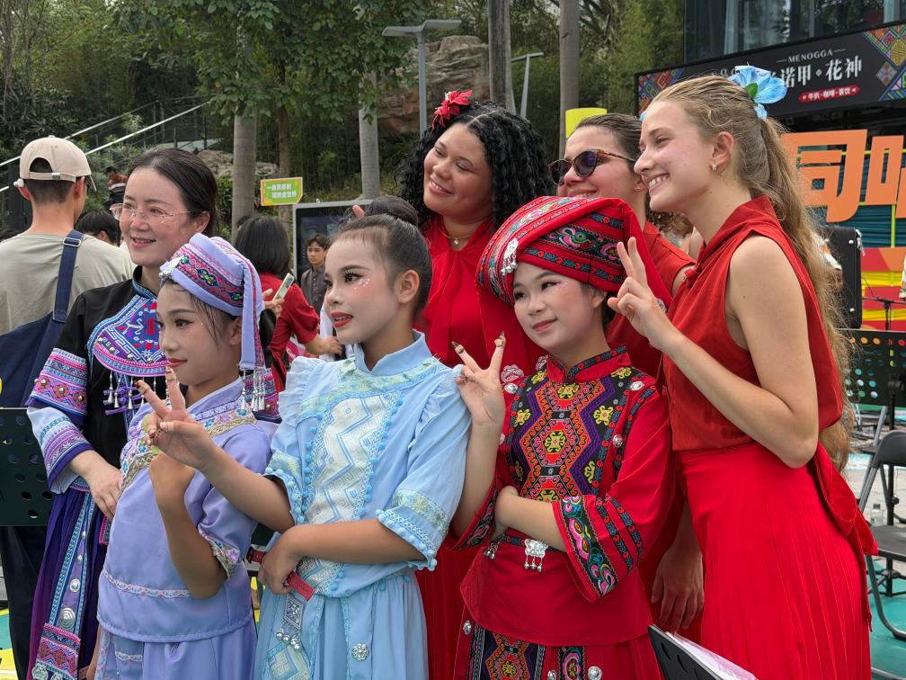 Membros da Orquestra Forte de Copacabana, do Brasil, posam para uma foto com crianças vestidas com trajes étnicos após uma apresentação na cidade de Nanning, na Região Autônoma da Etnia Zhuang de Guangxi, no sul da China, em 17 de abril de 2026. (Xinhua/Zhao Huan)
