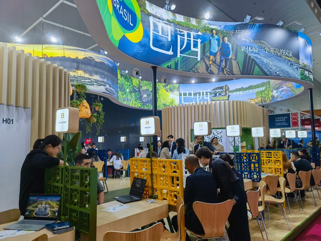 Expositores e visitantes conversam na área de exposição do Brasil na ITB China 2026, em Shanghai, no leste da China, em 26 de maio de 2026. (Xinhua/Chen Aiping)