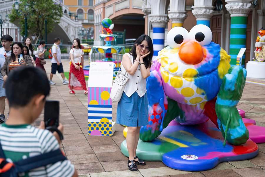 Uma turista posa para uma foto com uma obra de arte em exposição durante a exposição especial "Dopamina: Fonte da Felicidade" no Venetian Macau, em Macau, no sul da China, em 29 de julho de 2025. (Xinhua/Cheong Kam Ka)