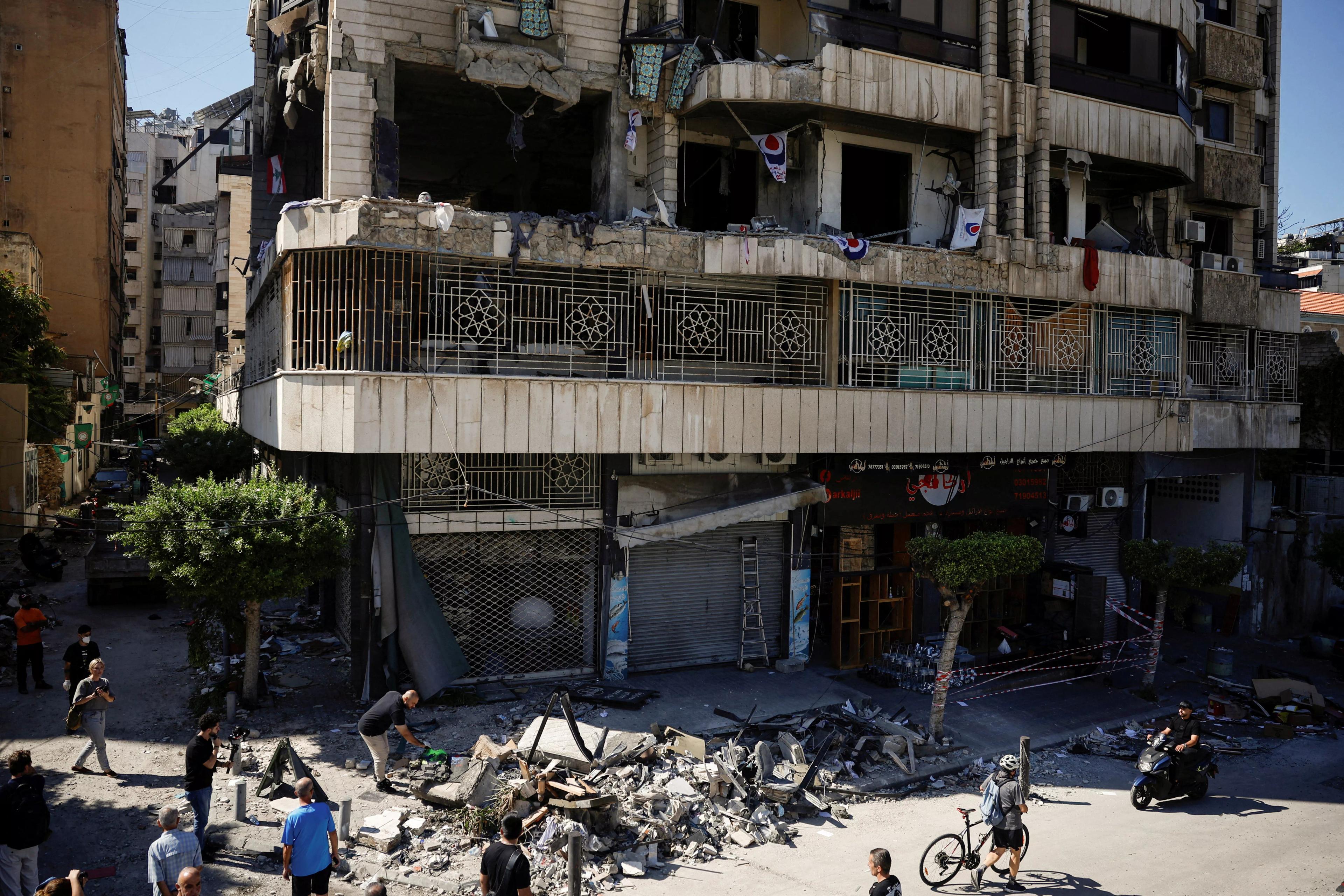 Pessoas observam prédio destruído no local de um ataque israelense na região central de Beirute